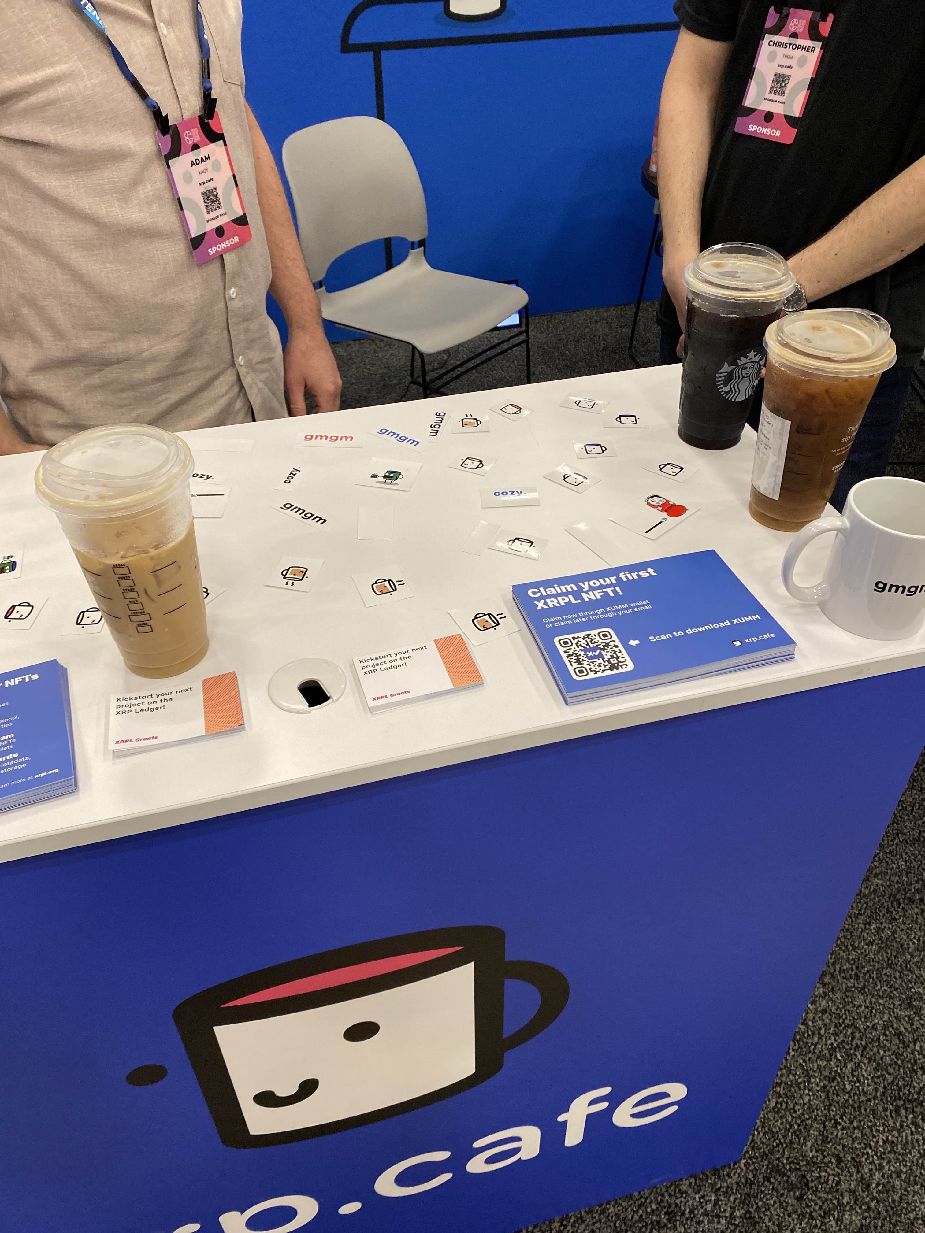 xrp.cafe booth table with stickers and merch